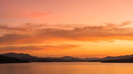 Obraz premium Sunset over calm water with silhouetted mountain range