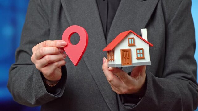 A businesswoman holds a house and a geolocation symbol. This is her place of work and residence. Relocation is based on a work offer.