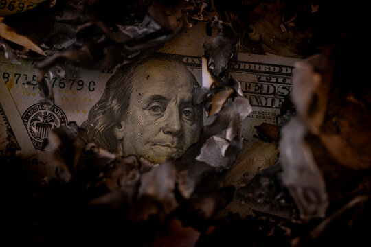 Close-up of US one hundred dollar bills covered with burnt ash and charred paper remnants