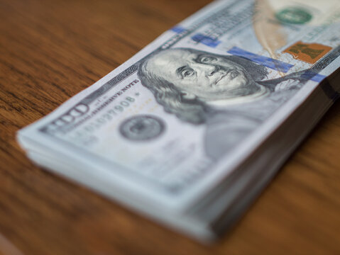 Stack of American 100 Dollar Bills on Wooden Table