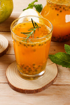 Refreshing glass of passion fruit juice with natural pulp and rosemary garnish served on rustic wooden table
