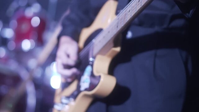 A musician playing an electric guitar on stage with professional lighting and audio equipment during a live event.