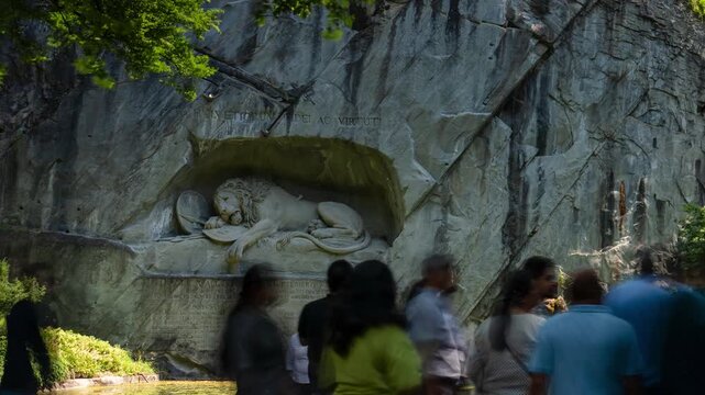 Lucerne Lion Monument time lapse with tourists visiting the famous rock relief sculpture carved into a cliff in Switzerland with reflections in a pond