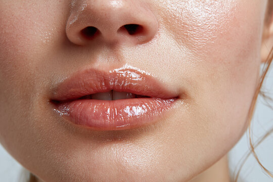 Glossy natural lips close up with smooth skin texture and subtle reflected light, sensual beauty detail showcasing hydrated lip gloss and healthy complexion