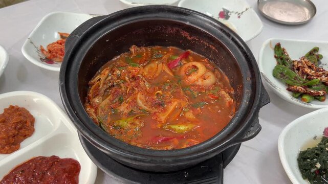K-food Myeolchi Ssambap (Korean spicy braised anchovy stew) boiling in an earthenware pot with side dishes in Tongyeong 멸치쌈밥