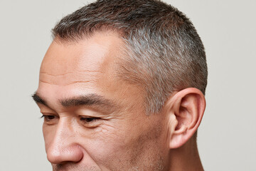 Fototapeta premium Gray cropped hair closeup of male scalp and temple showing skin texture and subtle emotion, natural light editorial portrait