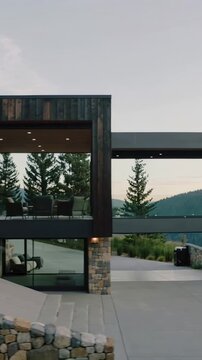 Vertical video: Panning camera from window revealing hillside house with deck showcasing form