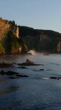 Vertical video: Swell pushing wave striking rock stack at coastal cliffs, sending spray and mist