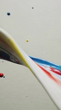 Vertical video: Impact launching paint mass unfolding into ribbon at studio wall, shedding droplets