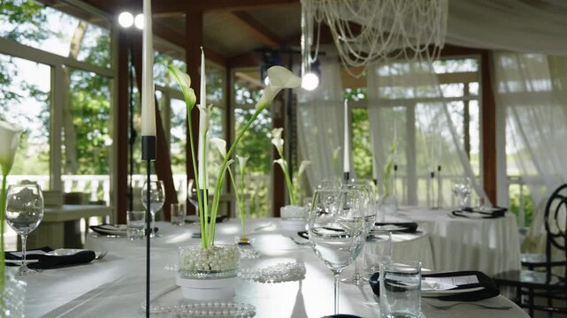 Elegant wedding reception table features floral centerpieces, glassware, and a beautifully arranged setting with natural light streaming in