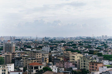 Fototapeta premium Cityscape of dense urban neighborhood with multi-story buildings under cloudy sky, distant skyline visible in background