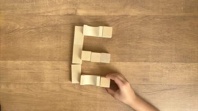 Child Completes the Letter E Shape with Natural Wooden Blocks, 4K