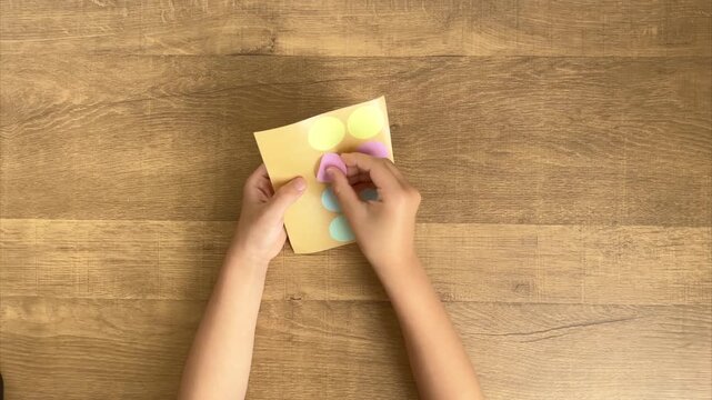 Child Puts a Pink Round Sticker Back onto the Sticker Sheet, 4K
