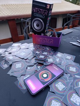 Hitster - Jogo de cartas e m&uacute;sica. O objetivo &eacute; simples: voc&ecirc; n&atilde;o precisa ser um especialista em m&uacute;sica, basta reconhecer os sucessos e organiz&aacute;-los em uma linha do tempo cronol&oacute;gica.