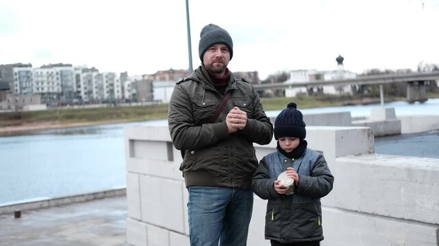 Loving father walking with little son boy on city river quay, chilly weather. Caring dad enjoying autumn family weekend walk. Together time theme. Paternal Care. Urban Local Tourism, parental support.