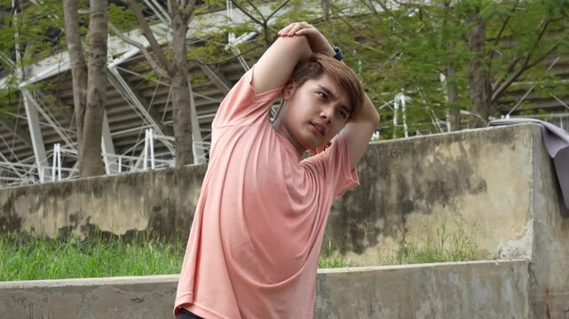 Teenager bending sideways stretching outdoors near stadium, highlighting youth lifestyle, fitness, wellness, and healthy activity in cheerful urban environment with daylight, and positive atmosphere