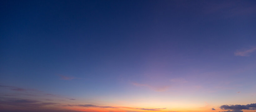 Vibrant Sunset Sky with Colorful Clouds,A breathtaking view of the twilight sky featuring a gradient of deep blue transitioning into warm golden and orange hues with soft cloud formations, perfect for