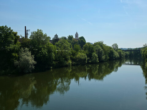 germany, calm neckar river reflecting green trees with stunning riverside view toward historic st blasius church in sunny summer landscape