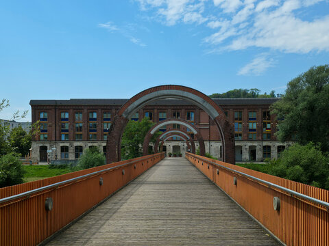 germany, charming ottosteg footbridge crossing neckar river beside impressive red brick building in peaceful plochingen summer cityscape