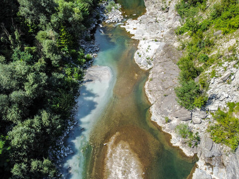 Sewage discharge flowing into a clean river aerial drone view. Wastewater entering river. Pollution from sewage pipe flowing into clean river from above.