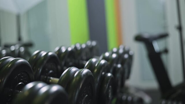 row of dumbbells arranged neatly in a gym. This setting highlights fitness training with a background of other gym equipment