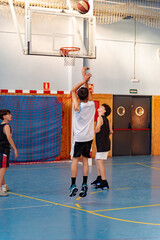 Obraz premium Young athletes training and playing basketball on court, boy jumping attempting to score a point during active game