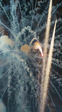 Vertical video: Bursting shells sending golden sparks over night sky for festival, comet rising