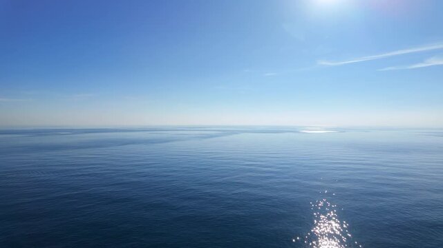 Panning wide shot of peaceful calm blue mediterranean sea with distant fishing boats.