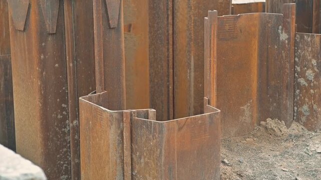 Steel sheets are being placed in an excavation site to provide support during construction. The focus is on the structural elements that ensure stability in the area where work is taking place