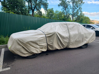 Car shielded by nylon cover in driveway keeping vehicle protected from rain sun and dirt © Harmony Video Pro