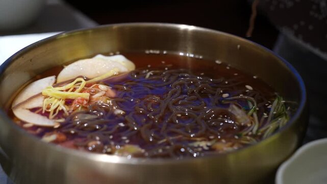 Eating korean grilled cold noodles by chopsticks, close up.