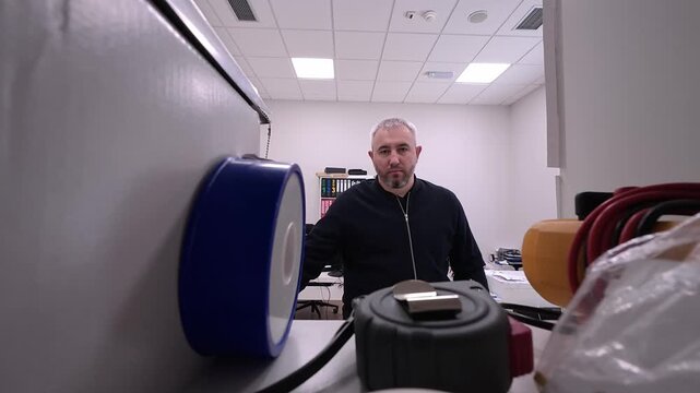 A video shot from inside a tool cabinet, capturing the moment a man opens the door from the outside. The footage shows the door swinging open to reveal a bright office, framed by the light. 