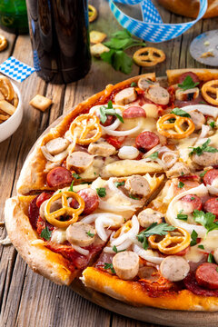 Oktoberfest Pizza with various bavarian sausages, beer and pretzels, beer snacks with festive decorations and bavarian flags, Oktoberfest party and picnic food idea, copy space
