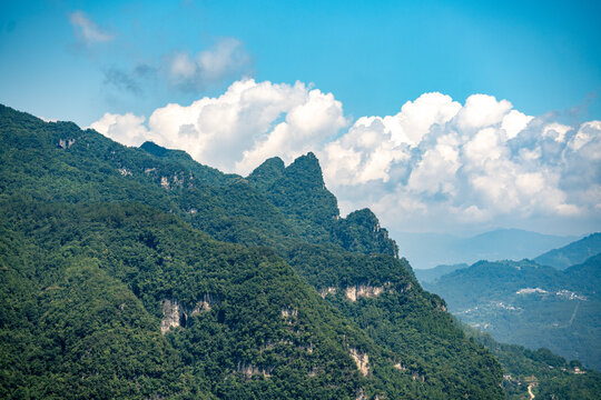 The lush green mountains rise above the Three Gorges Reservoir near Yichang in China under a bright blue sky with white clouds during the summer season