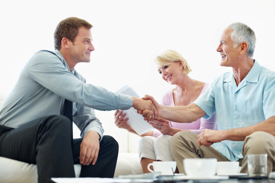 Handshake, consultant and senior couple in home for trust agreement, asset transfer and approval. Retirement, financial advisor and people shaking hands for fiduciary duty, fraud protection and happy