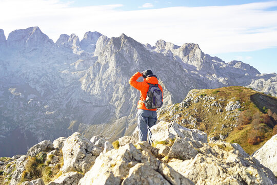 Hiker shields eyes scanning jagged limestone ridges across Prokletije National Park. Represents route-finding instinct, mountain orientation skill, and analog navigation without digital devices. 