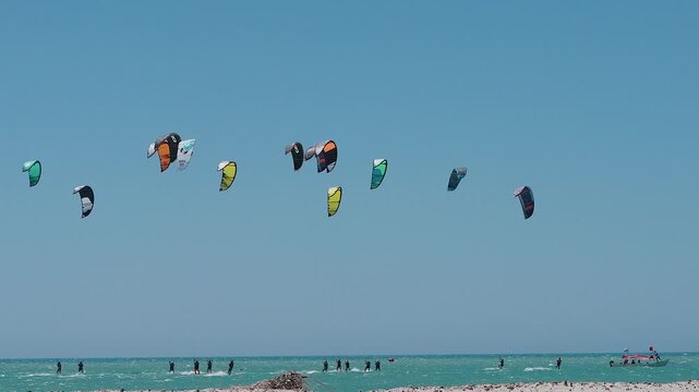group of kitesurfers riding on the sea in a competition