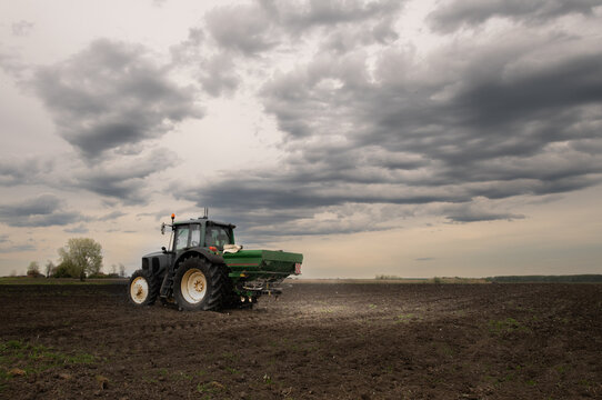 Tractor spreading artificial fertilizers in field