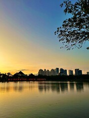 Fototapeta premium Beautiful City Skyline Reflection in Calm Water during a Golden Sunset