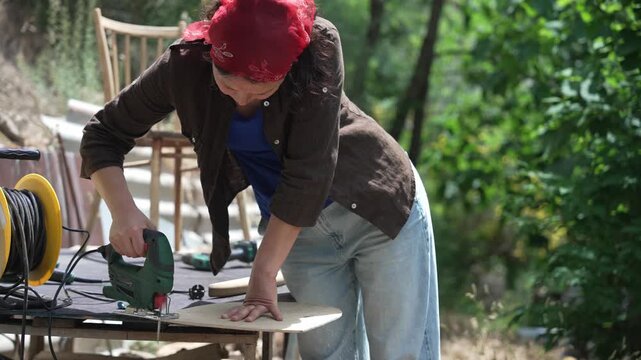 DIY furniture restoration by a woman, repairing a vintage wooden chair with hand tools in a outdoors workshop