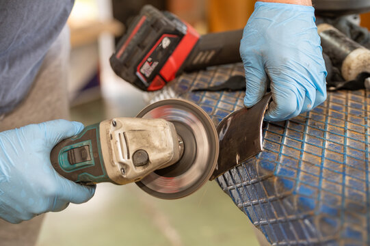 Mechanical grinding of a car's catalytic converter or exhaust pipe system with an angle grinder. Car repair workshop, metal production, and the concept of professional vehicle maintenance.