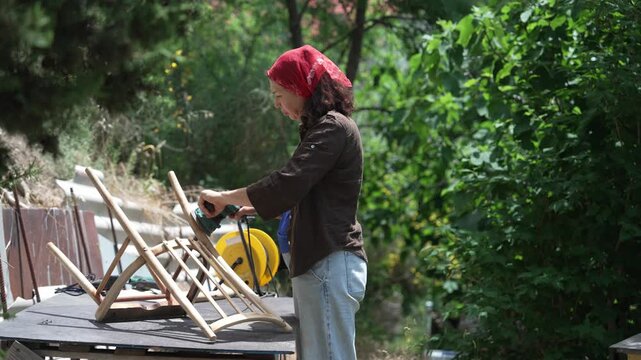 Woman sanding and restoring an antique wooden chair in village, home renovation and handmade craftsmanship