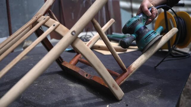 Woman sanding and restoring an antique wooden chair in village, home renovation and handmade craftsmanship