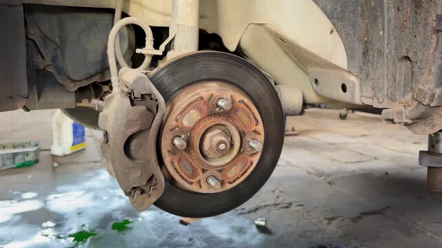 Close Up Of Car Disc Brake Rotor And Caliper During Vehicle Maintenance Service
