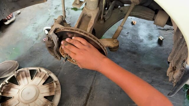 mechanic inspecting car brake caliper during routine brake system maintenance in auto workshop