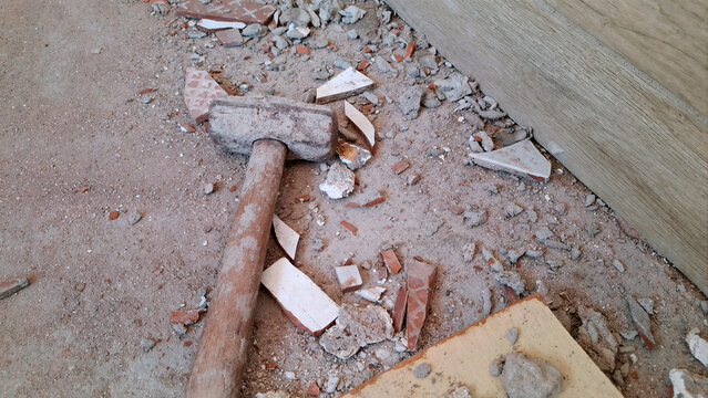 Sledgehammer and broken rubble on the floor of a construction site