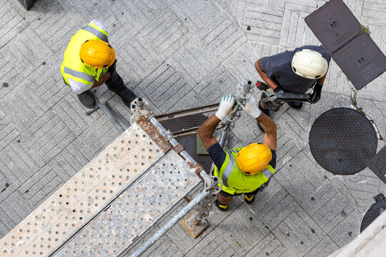 Aerial view of a group of construction workers in protective work wear assembling an european scaffolding