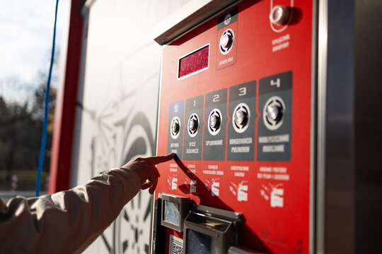 Hand pressing button on automated vending machine at manual carwash station.