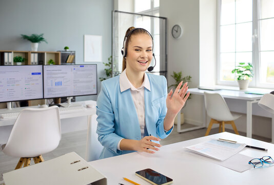 Operator woman with headset handles online call support. She greets clients in a bright office, delivering service and consultation to build trust. Customer care and communication concept