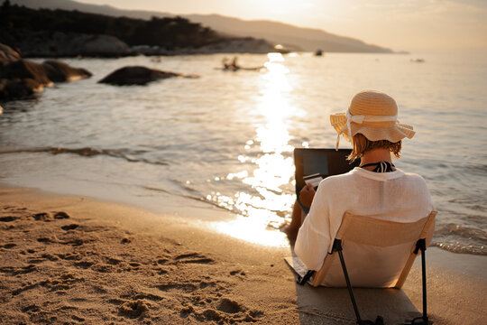 Woman enjoying sunset beach shopping with laptop and credit card